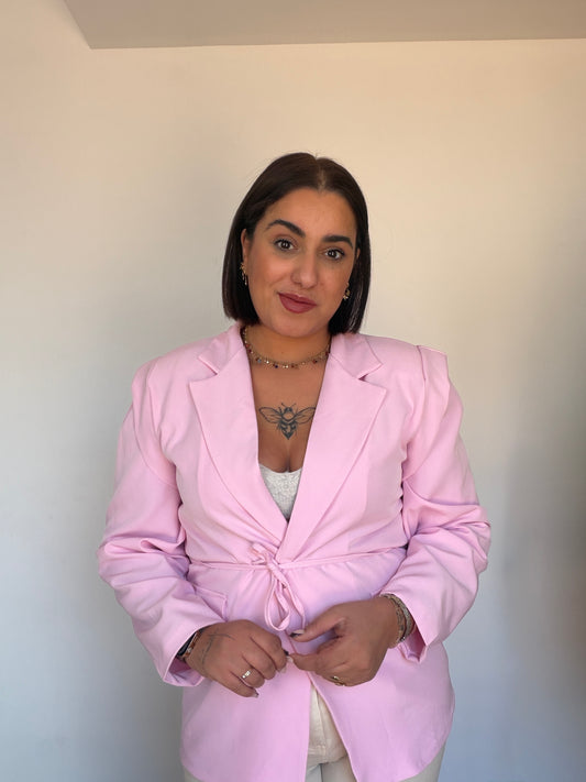 Detalle chaqueta rosa mujer con cinturón lazada ajustable.