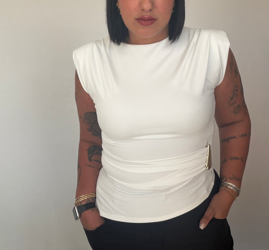 Primer plano del aplique dorado y drapeado lateral en camiseta de licra blanca