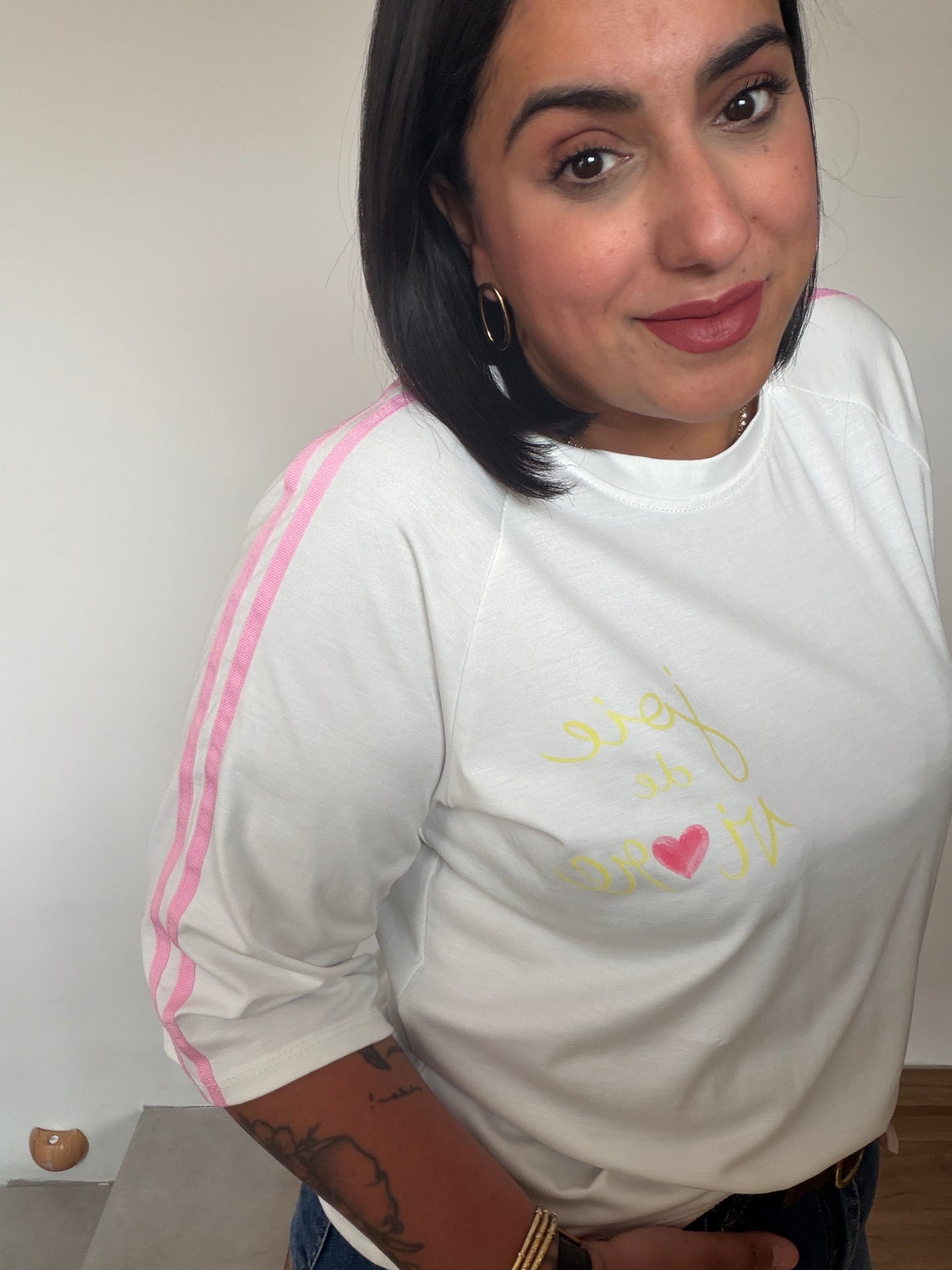 Modelo luciendo camiseta blanca con detalles retro sport en color rosa