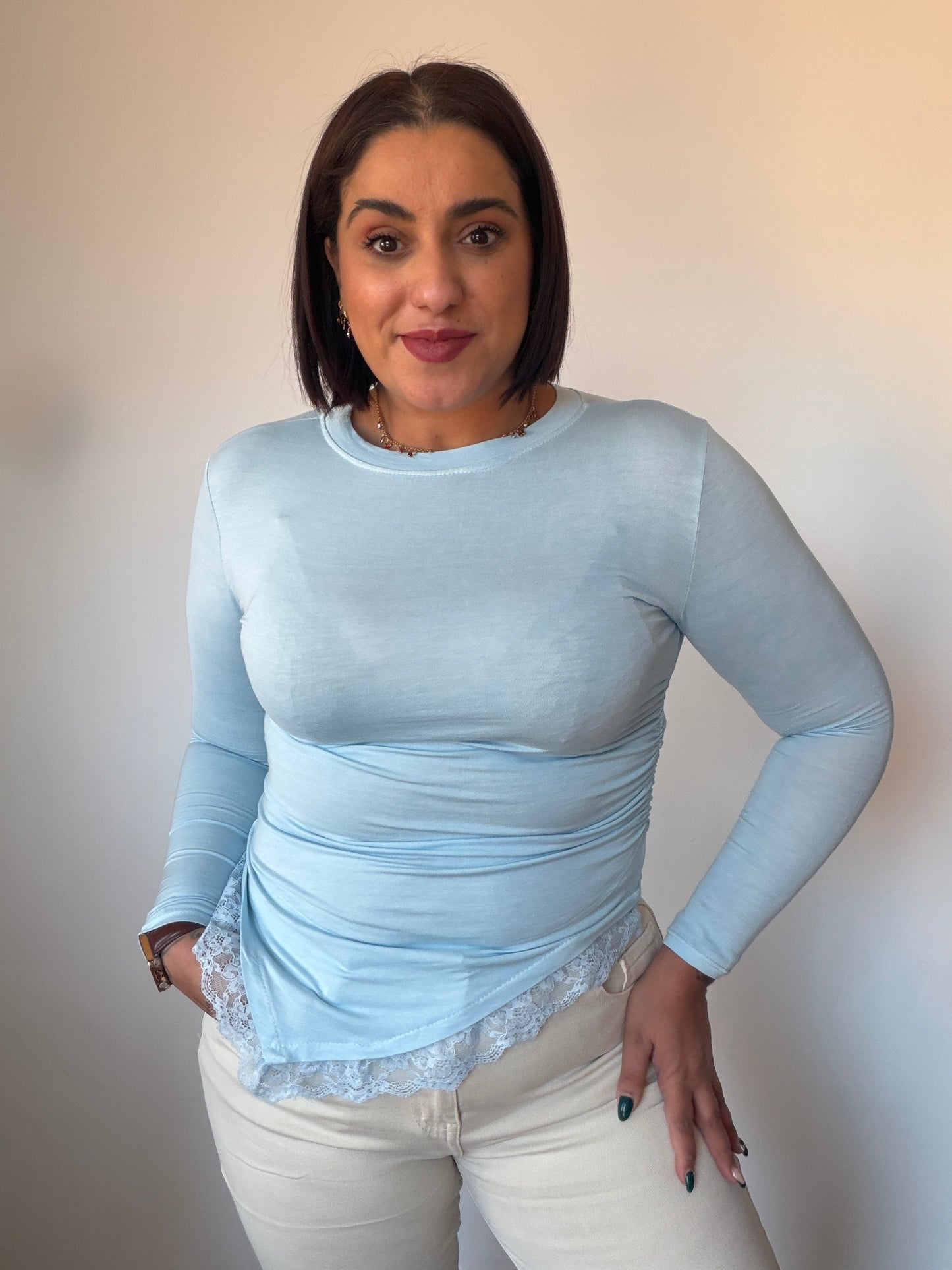 Blusa básica asimétrica color azul baby con detalle de encaje en el bajo.