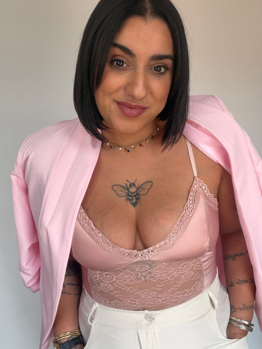 Mujer vistiendo body lencero rosa de raso con blazer rosa, look de fiesta elegante.