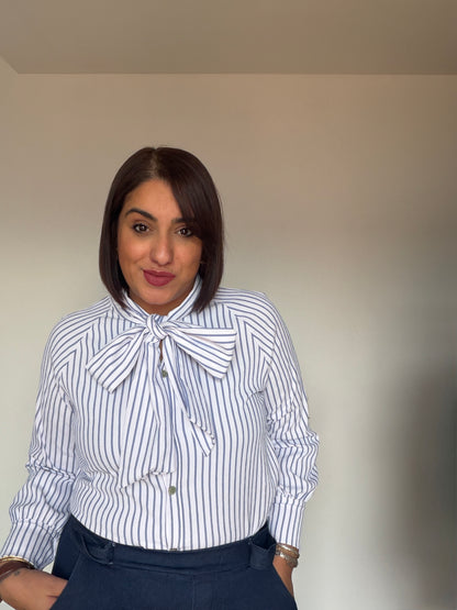 Camisa fluida rayas azul y blanco suave con lazo ajustable al cuello.