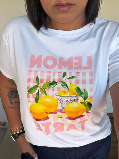 Detalle de camiseta blanca de algodón con gráfico de limones y fondo rosa pastel