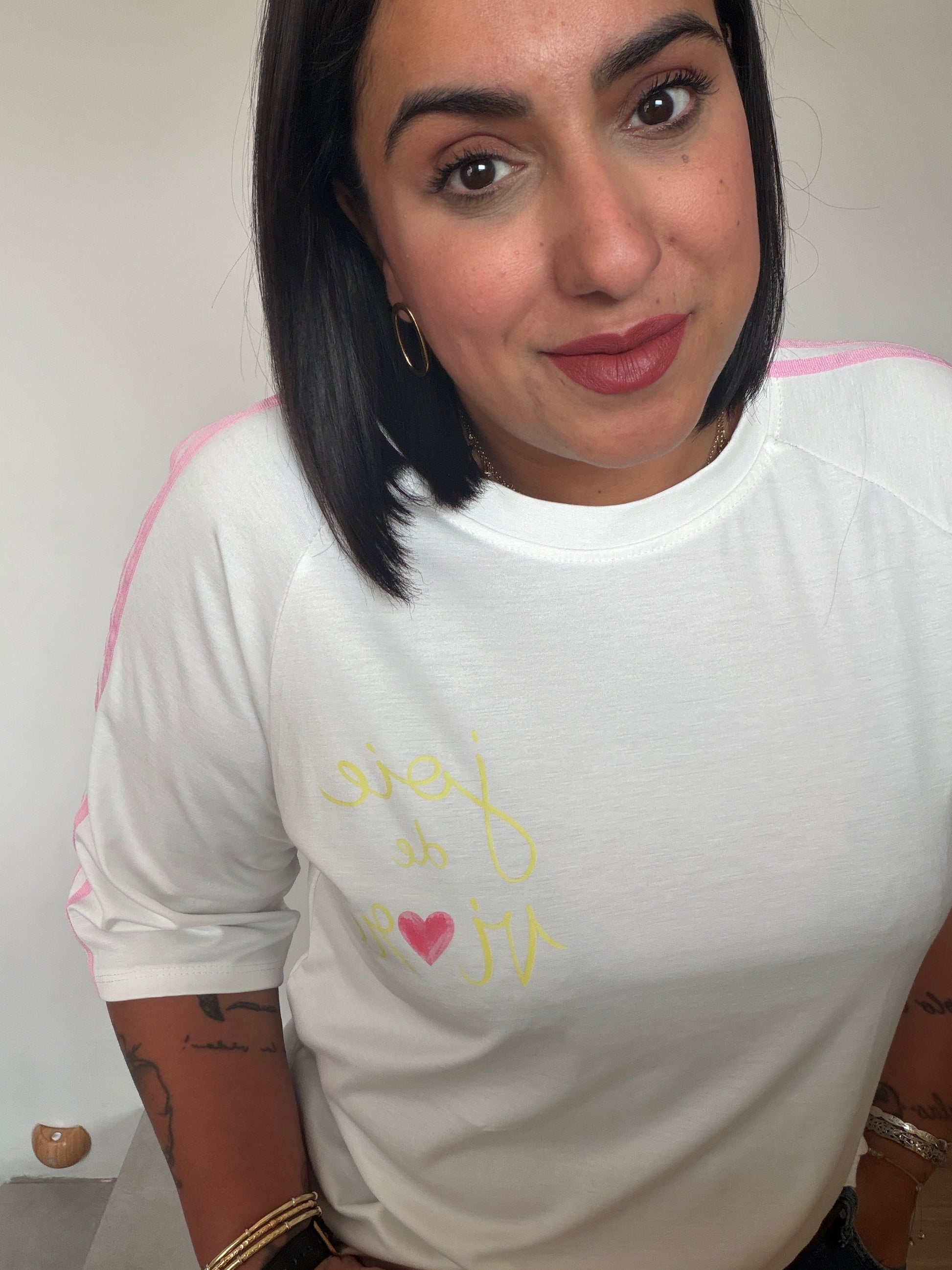 Primer plano de camiseta blanca casual con franjas rosas y corazón estampado Meknes Store