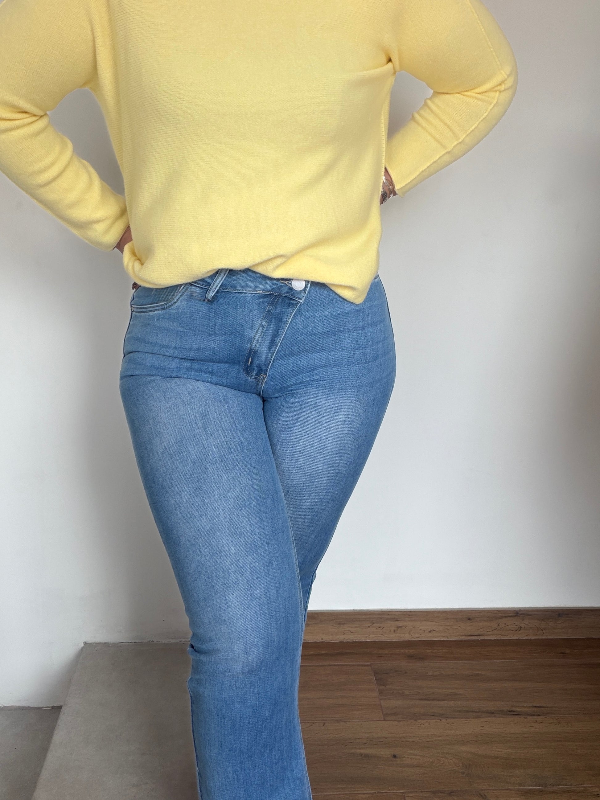 Primer plano cierre botón cruzado en jeans azules para afinar cintura.