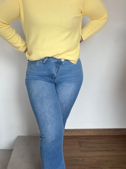 Primer plano cierre botón cruzado en jeans azules para afinar cintura.