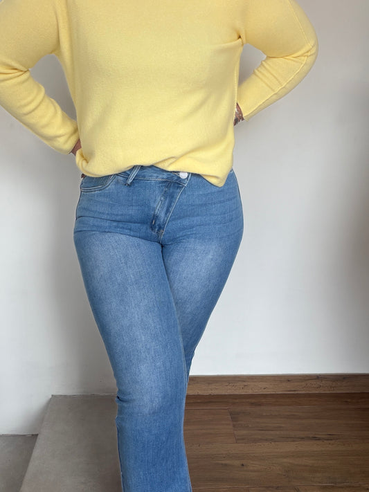 Primer plano cierre botón cruzado en jeans azules para afinar cintura.