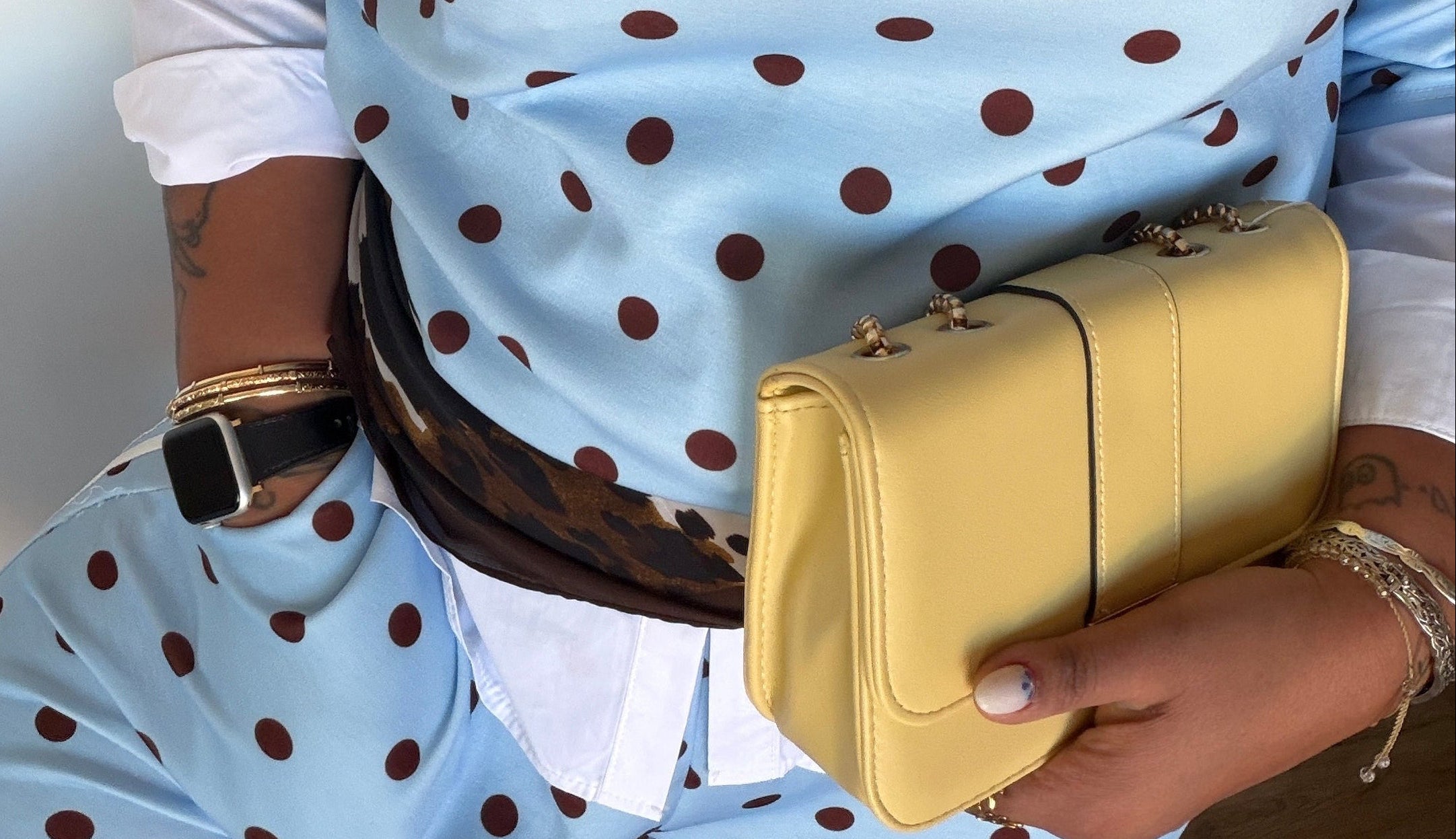 Detalle de contraste de color entre bolso mostaza y conjunto deportivo azul claro