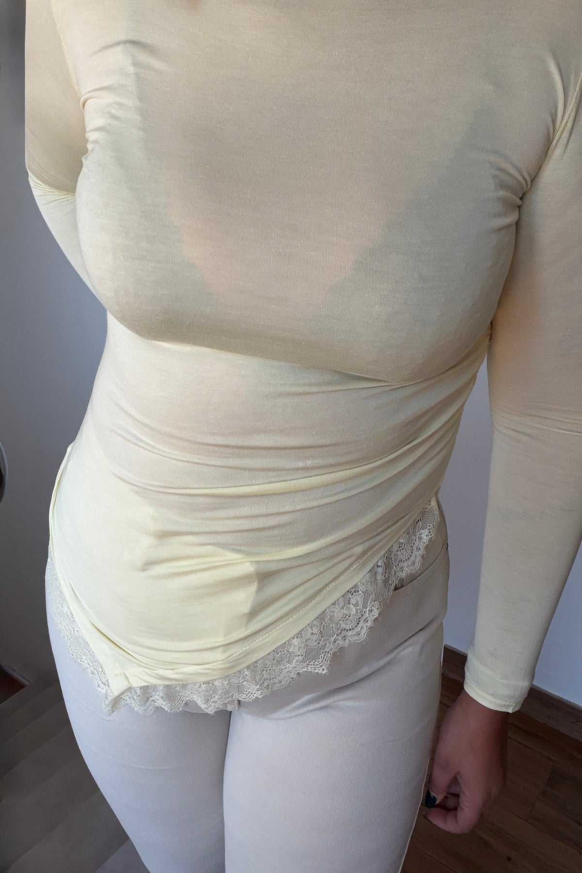 Primer plano del detalle de encaje en el bajo de la blusa asimétrica