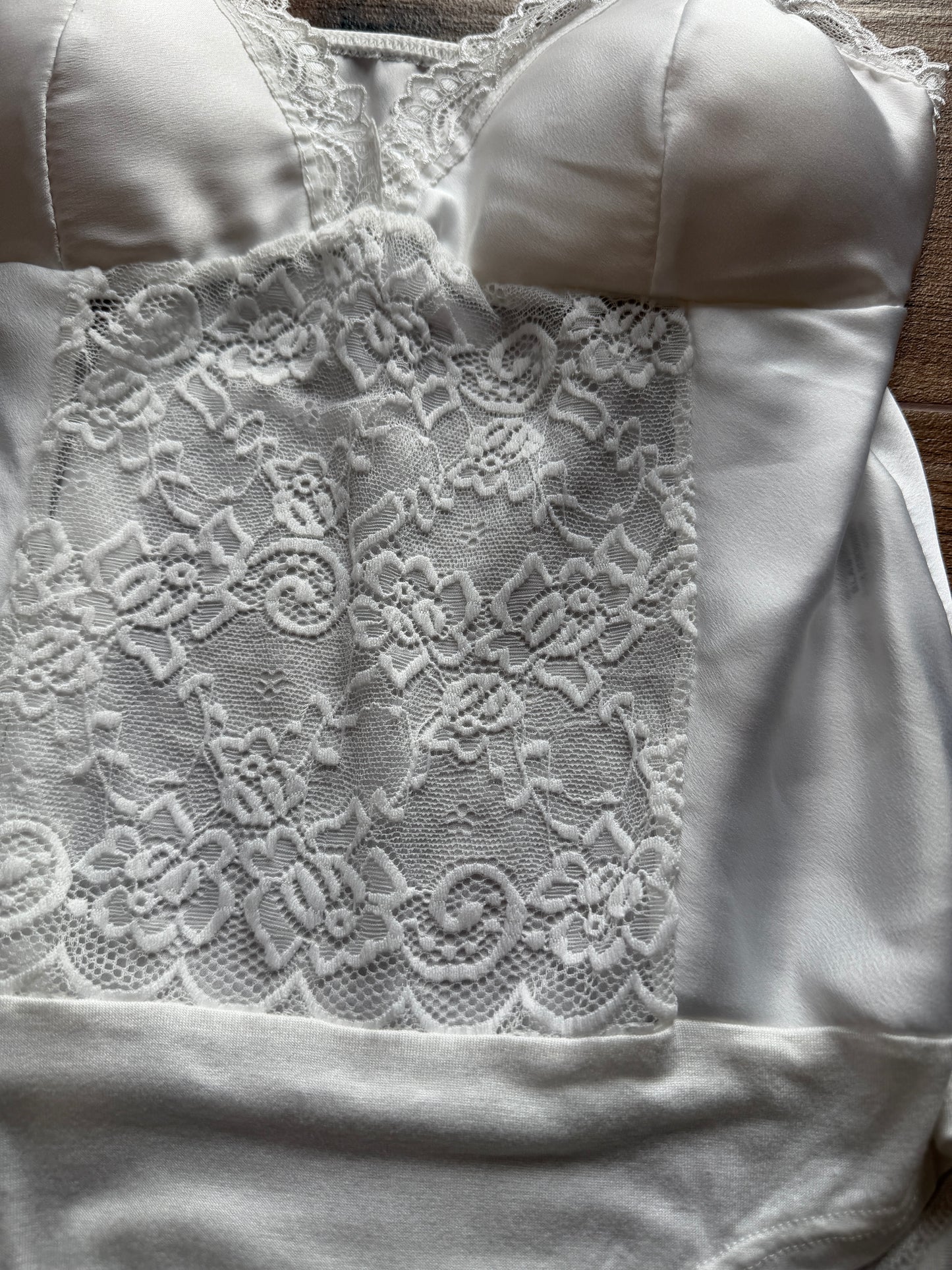 Detalle copa y escote body blanco satinado ajuste pecho.