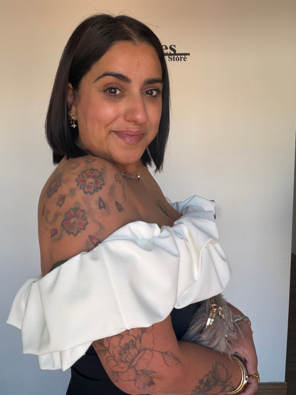 Perfil de mujer luciendo vestido bicolor ajustado mostrando el volumen arquitectónico del volante blanco