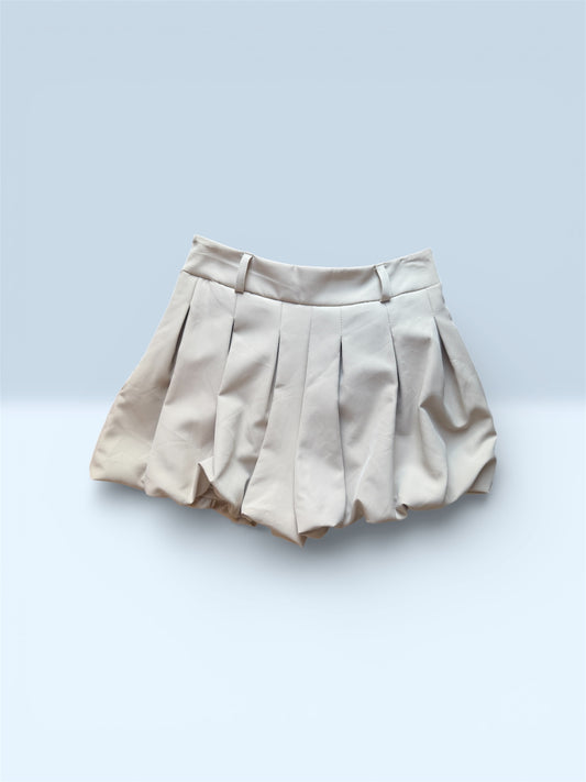 Detalle falda beige corta con vuelo y pliegues estilo bubble.