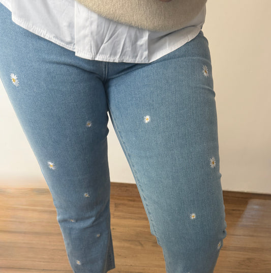 Detalle pantalón vaquero mujer azul claro con margaritas bordadas pequeñas.