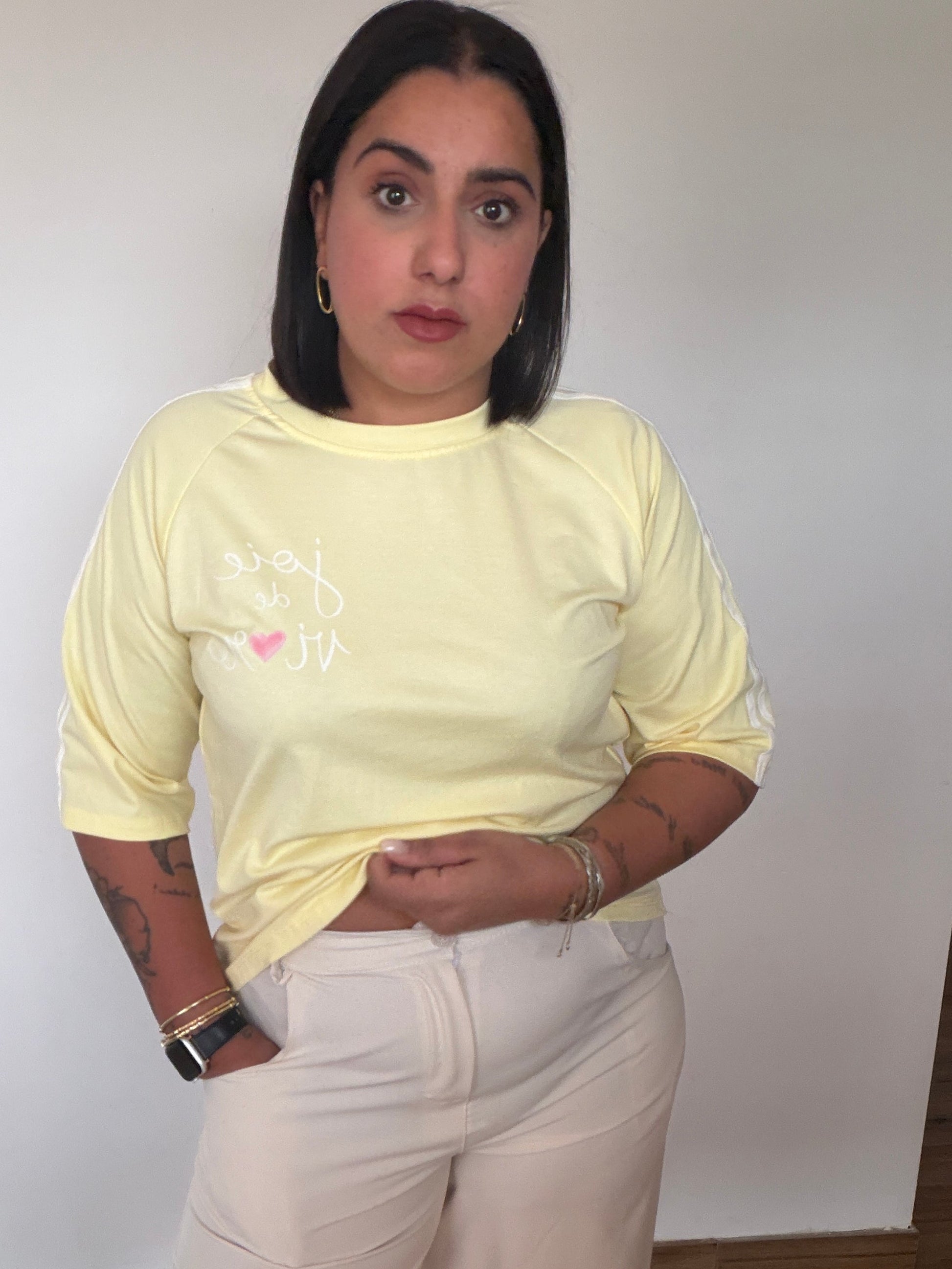 Modelo con camiseta amarilla pastel de manga tres cuartos y estética retro sport