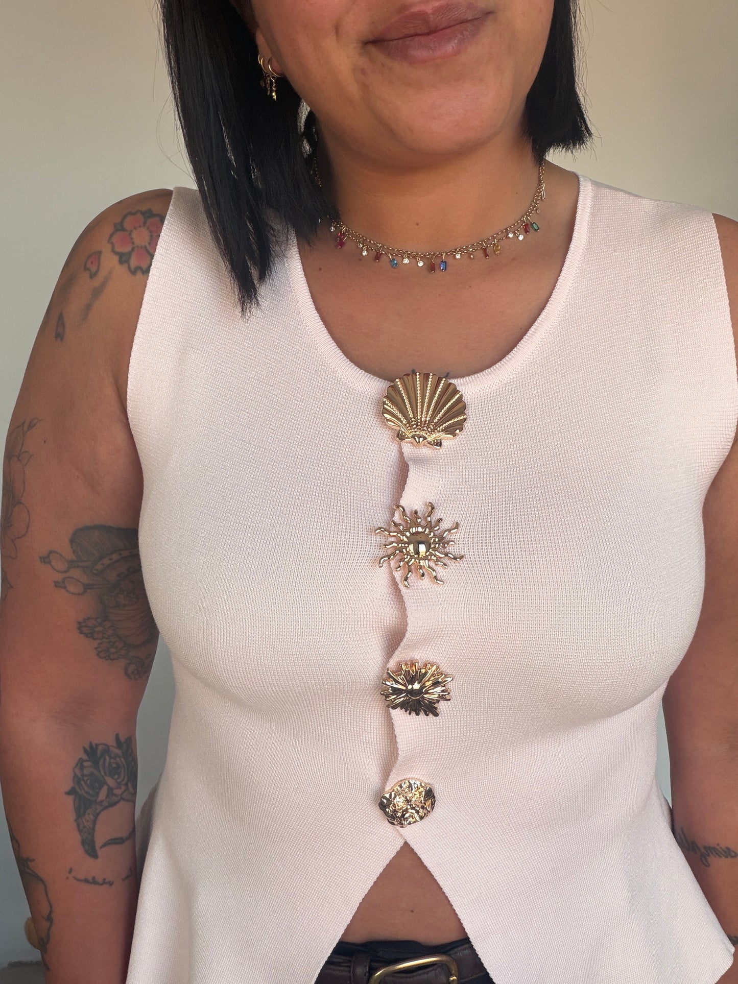 Outfit casual chic con top blanco de botones dorados y pantalón negro