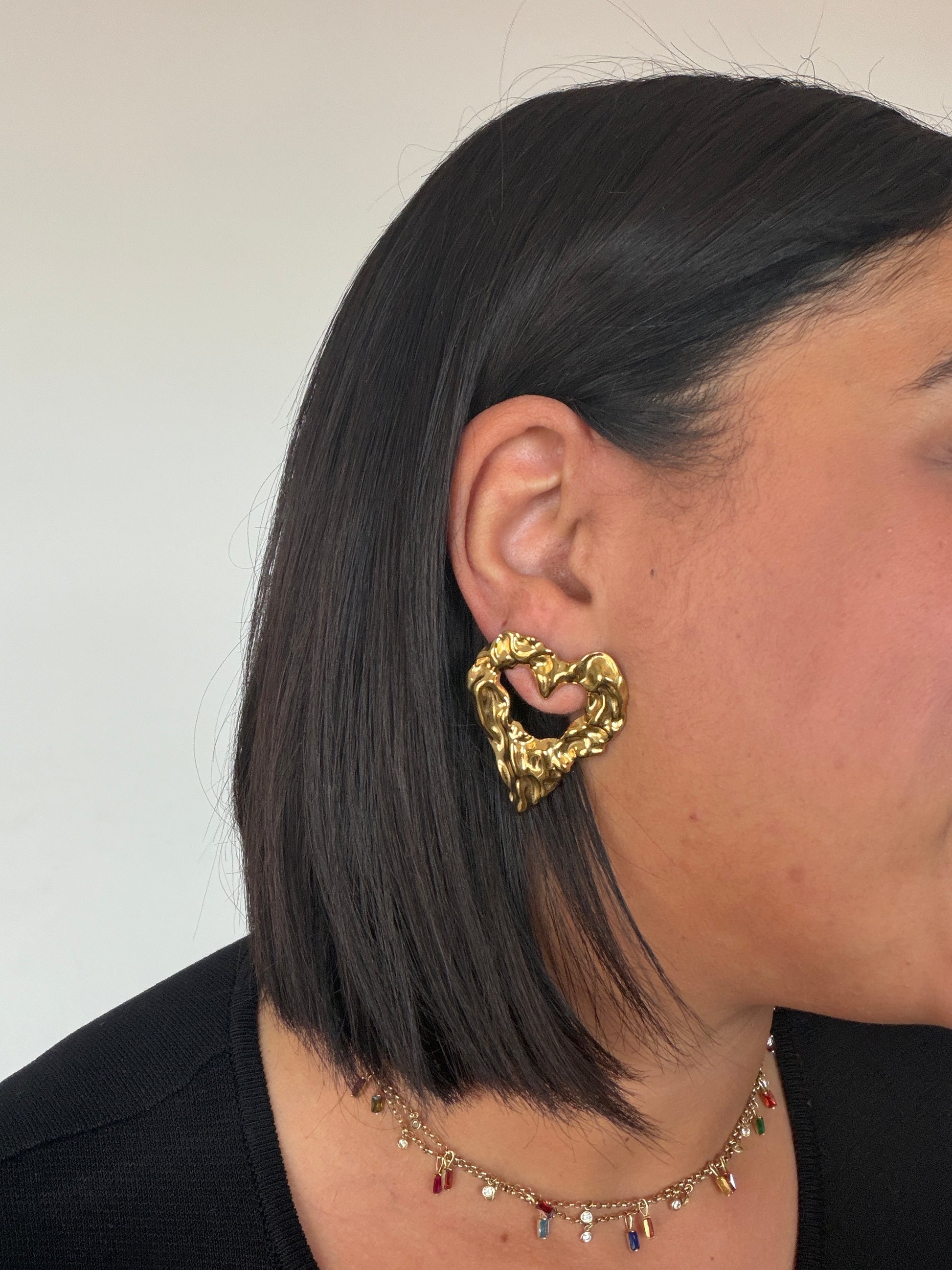 Perfil de mujer con pendientes maxi dorados estilo corazón asimétrico