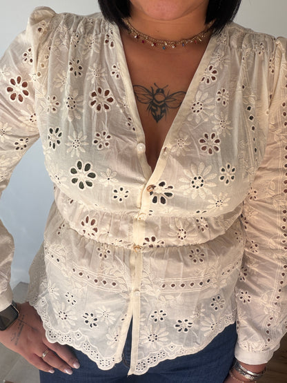 Outfit femenino con blusa bordada troquelada vainilla y vaqueros de talle alto