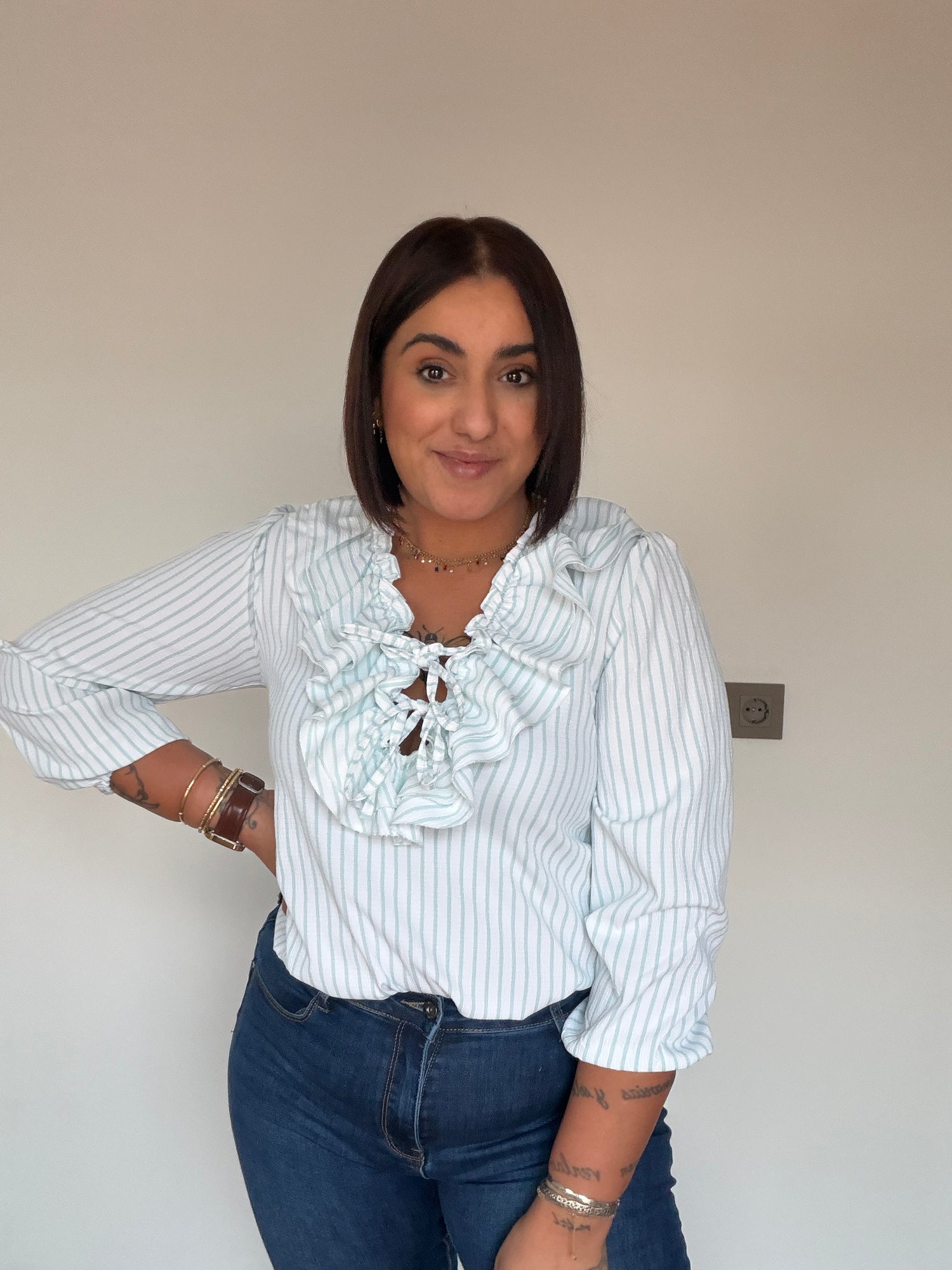 Outfit con vaqueros slim azul marino y blusa de rayas con volantes de Meknes Store