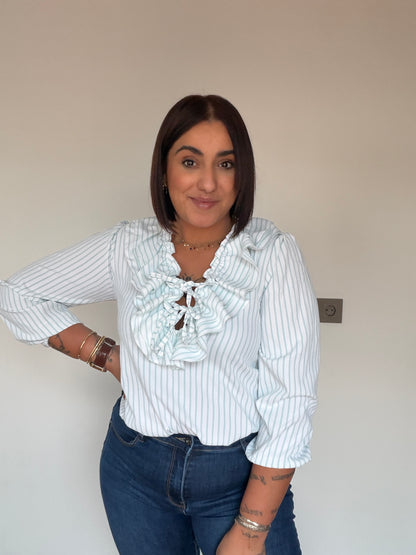 Outfit con vaqueros slim azul marino y blusa de rayas con volantes de Meknes Store