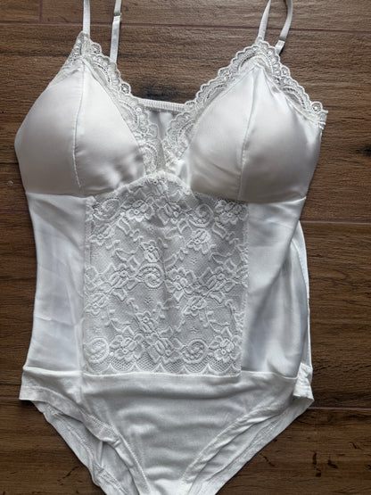 Primer plano encaje floral blanco en body lencero nupcial o fiesta.