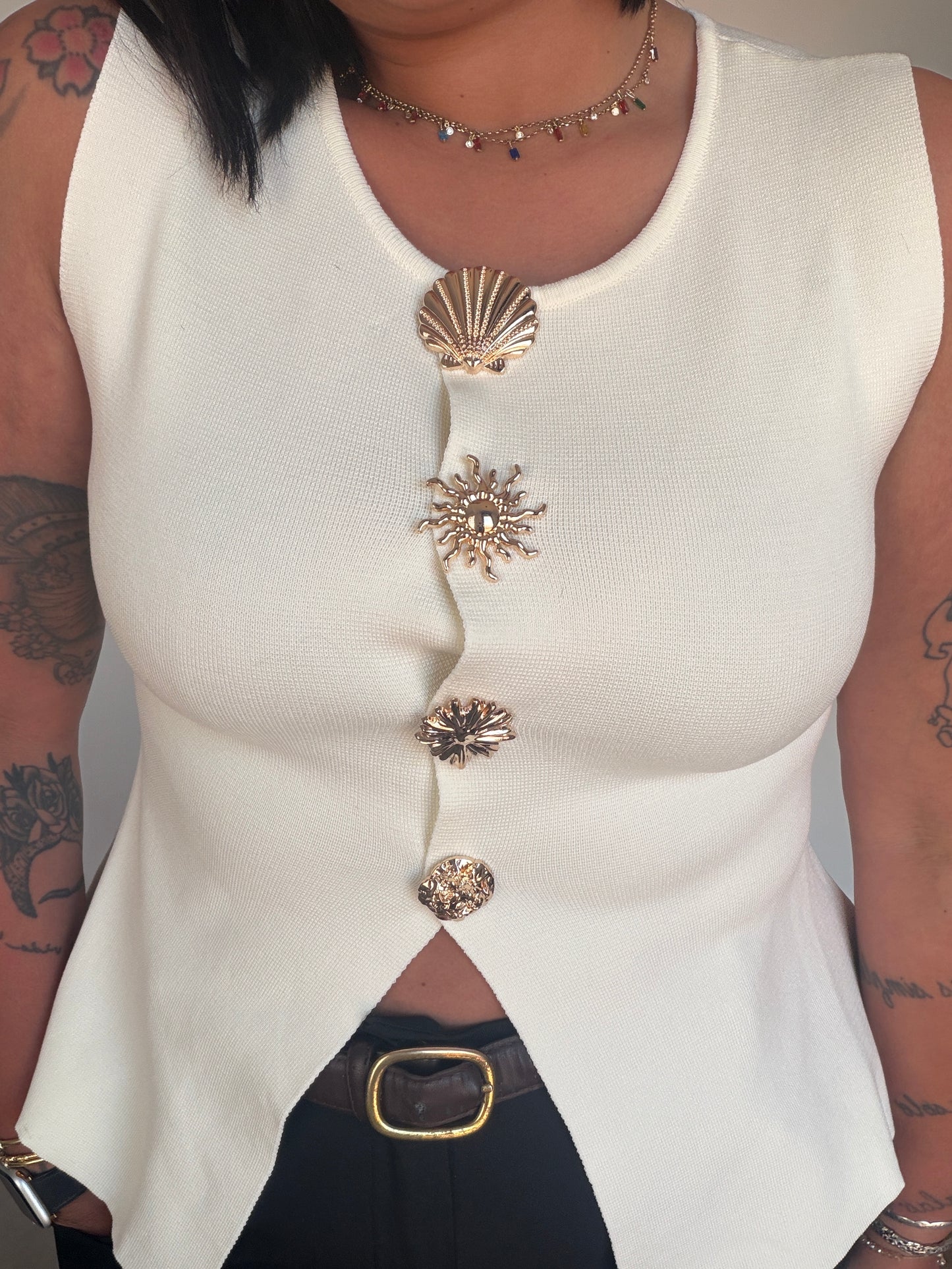 Top blanco fluido con abertura frontal asimétrica y botones joya