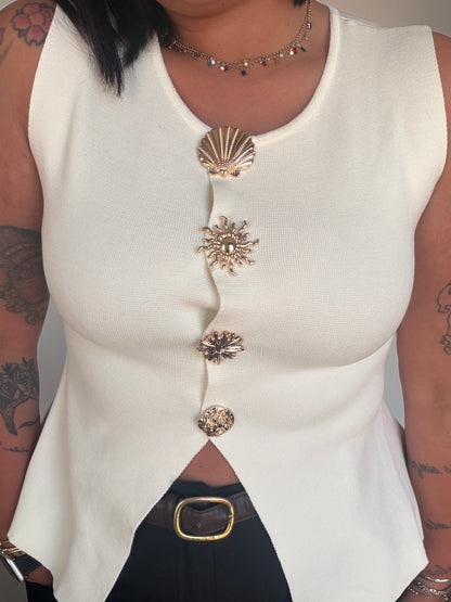 Top blanco fluido con abertura frontal asimétrica y botones joya