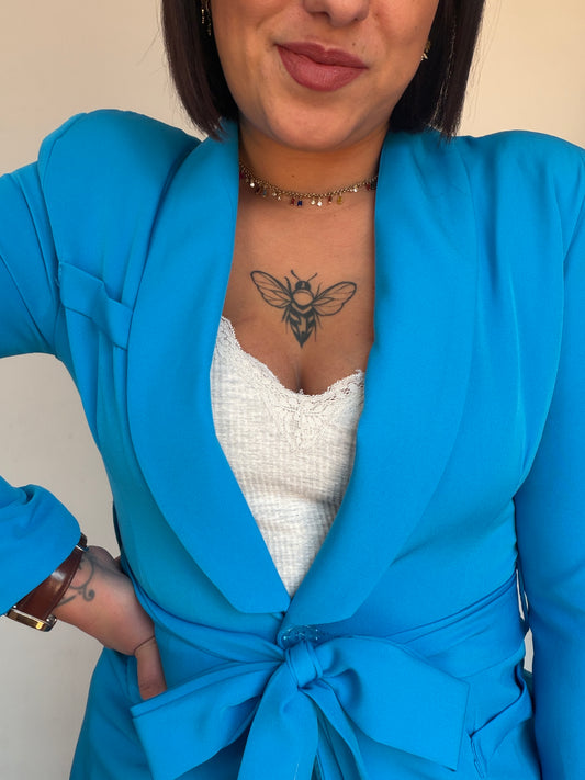 Detalle blazer cruzada azul con lazo a la cintura y top lencero.
